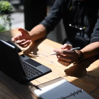 Student sitting a desk with a laptop open, explaining something.