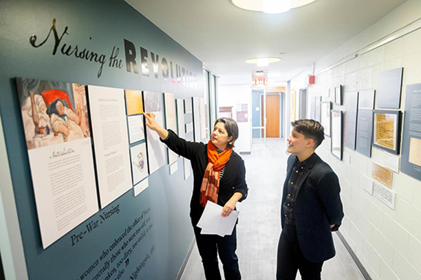 Curator Jessica Martucci, left, and guest curator Meg Roberts discuss the “Nursing the Revolution” exhibit at the Bates Center for the Study of the History of Nursing.