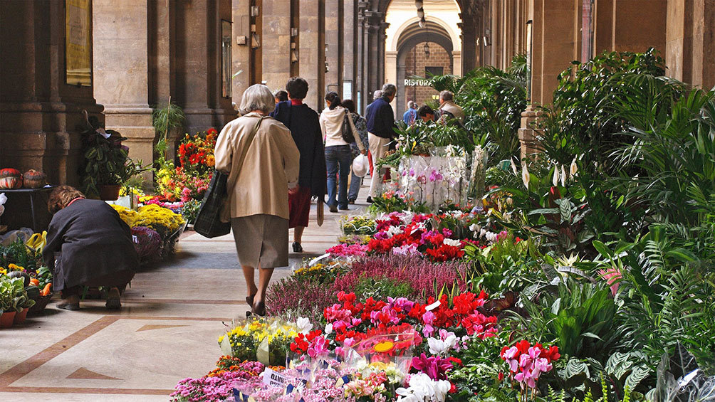 Image description: People walking through the flower market in Florence.
