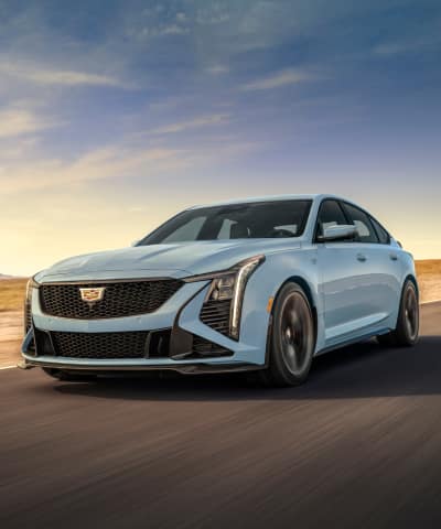 Cadillac CT5-V Blackwing driving down a road in a desert environment with partly cloudy blue skies in the background.