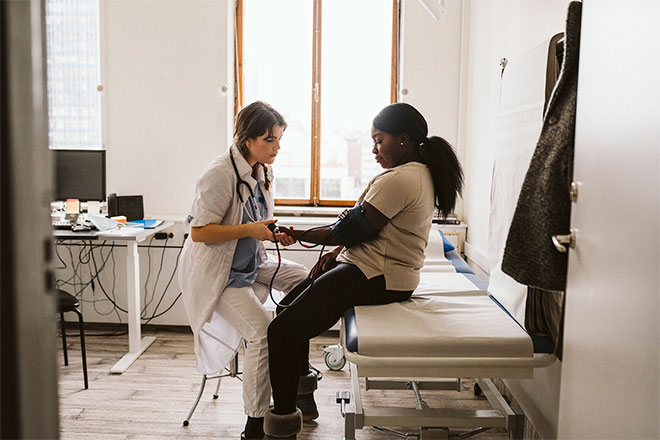 A doctor tests a patient's blood pressure in an office.
