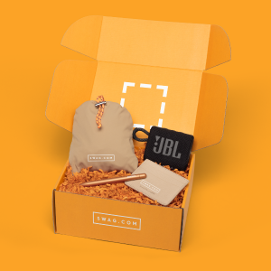 An orange box filled with orange crinkle paper, a custom speaker and other custom tech gifts, on an orange background.