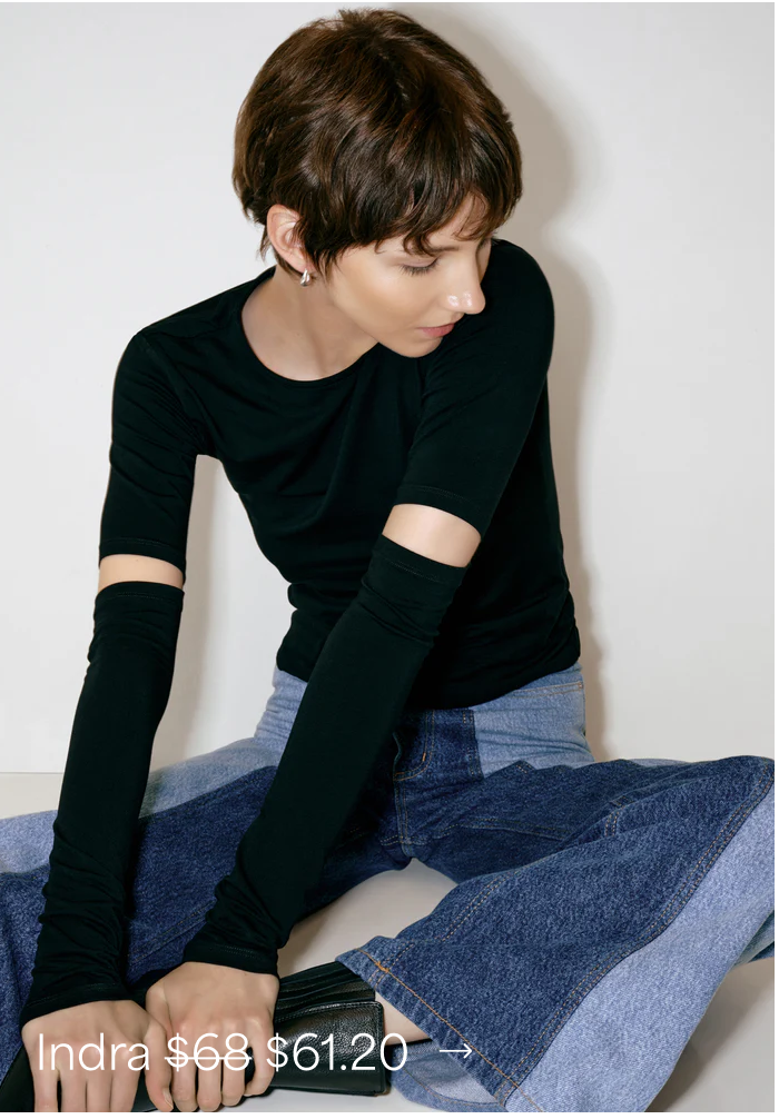 Julia in The Indra Top and two-tone wide-leg jeans looks down.