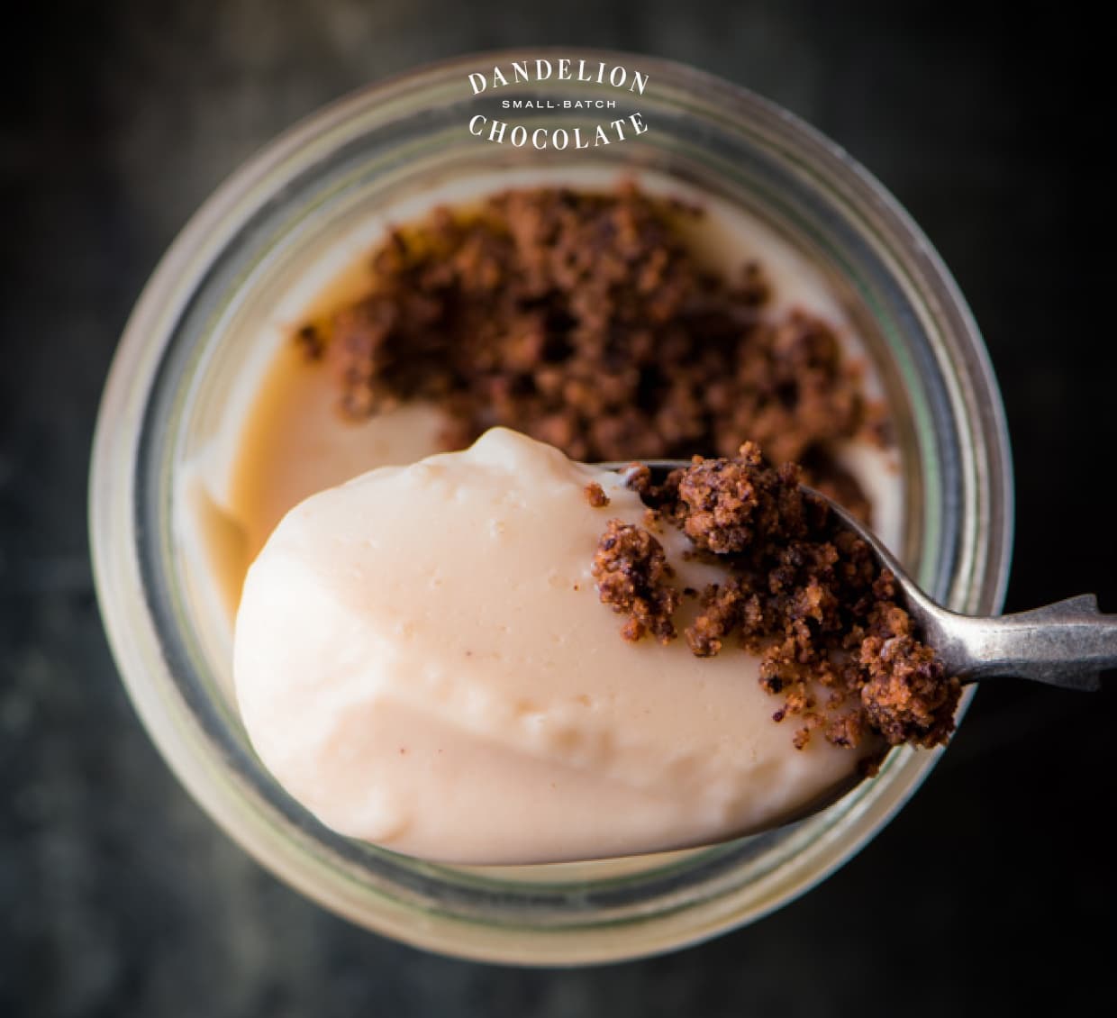 An overhead view of Lisa’s Nibby Panna Cotta. A spoonful holds a bite topped with cocoa nibs.