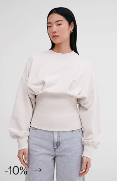 Xun wears The Maris Sweatshirt with voluminous sleeves and a ribbed, cinched waist over light-wash jeans.