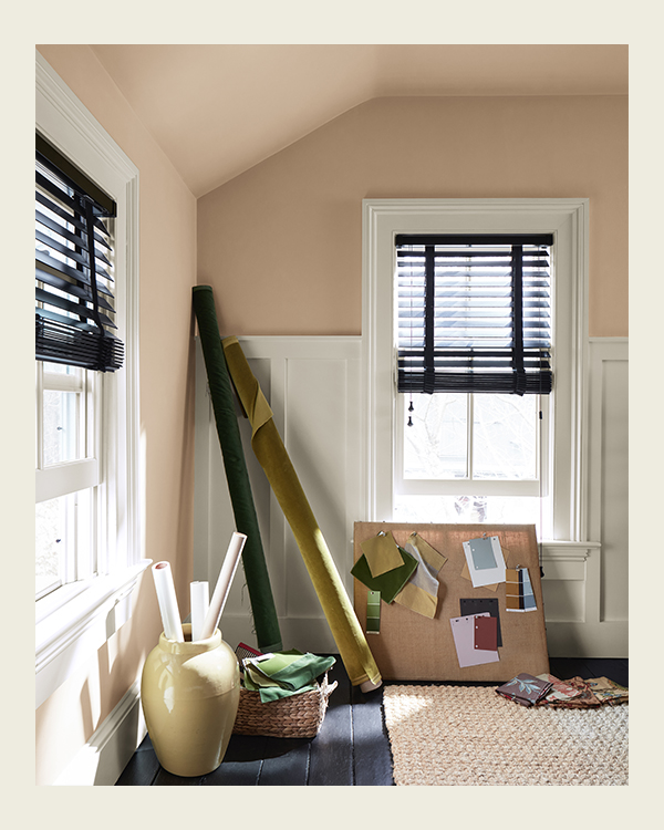 A beige painted craft room with a basket of linens, rolled up fabrics, and a moodboard with different color chips.