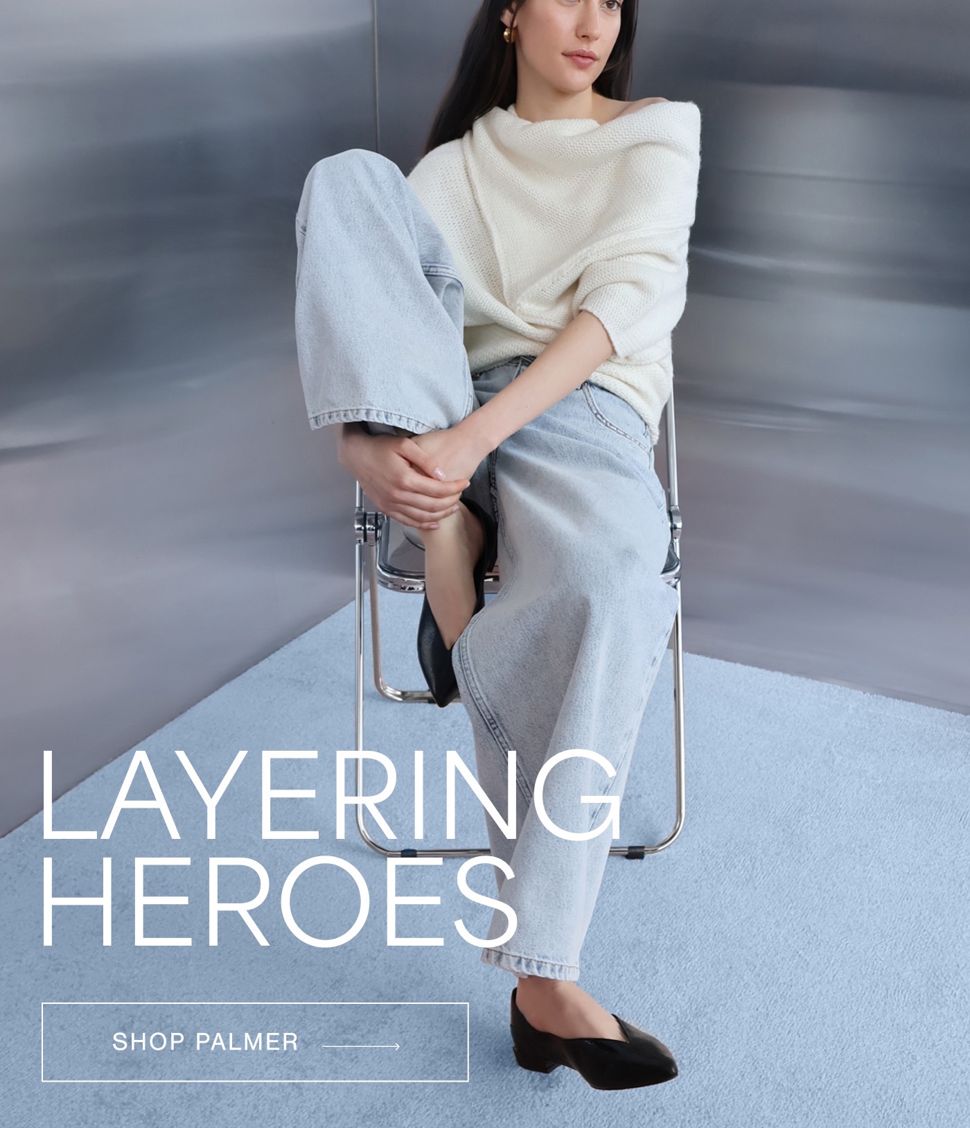 Milana sits casually on a chair wearing The Palmer Knit Top in off-white with light wash jeans and black shoes, alongside the text “LAYERING HEROES" and a "SHOP PALMER →" button.”