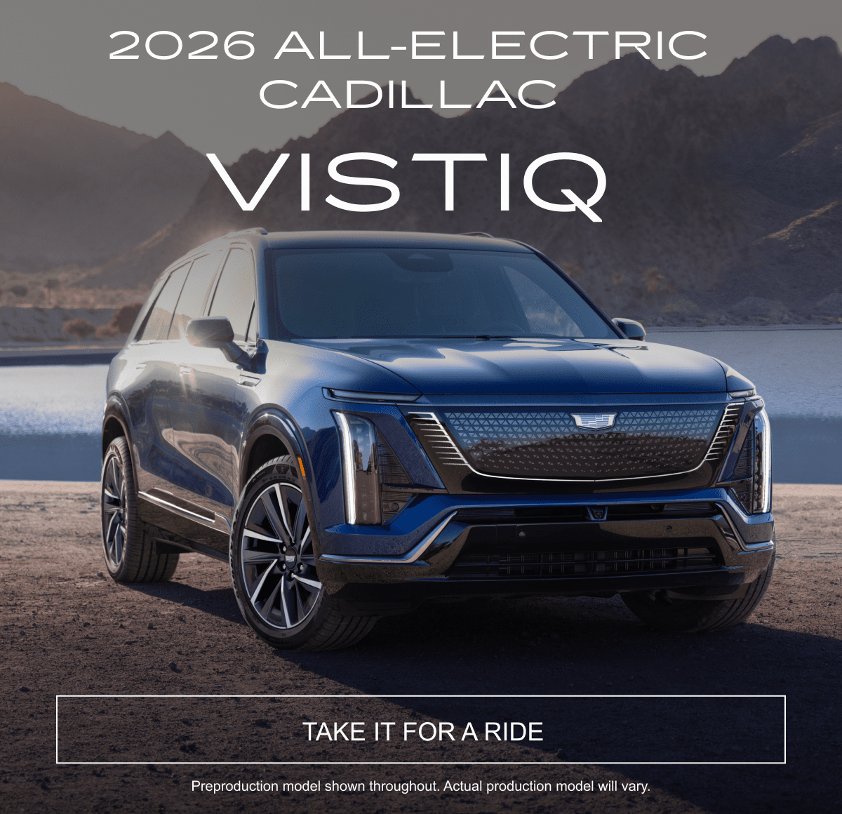 2026 Cadillac VISTIQ parked on a rocky road by a lake with mountains in the background.