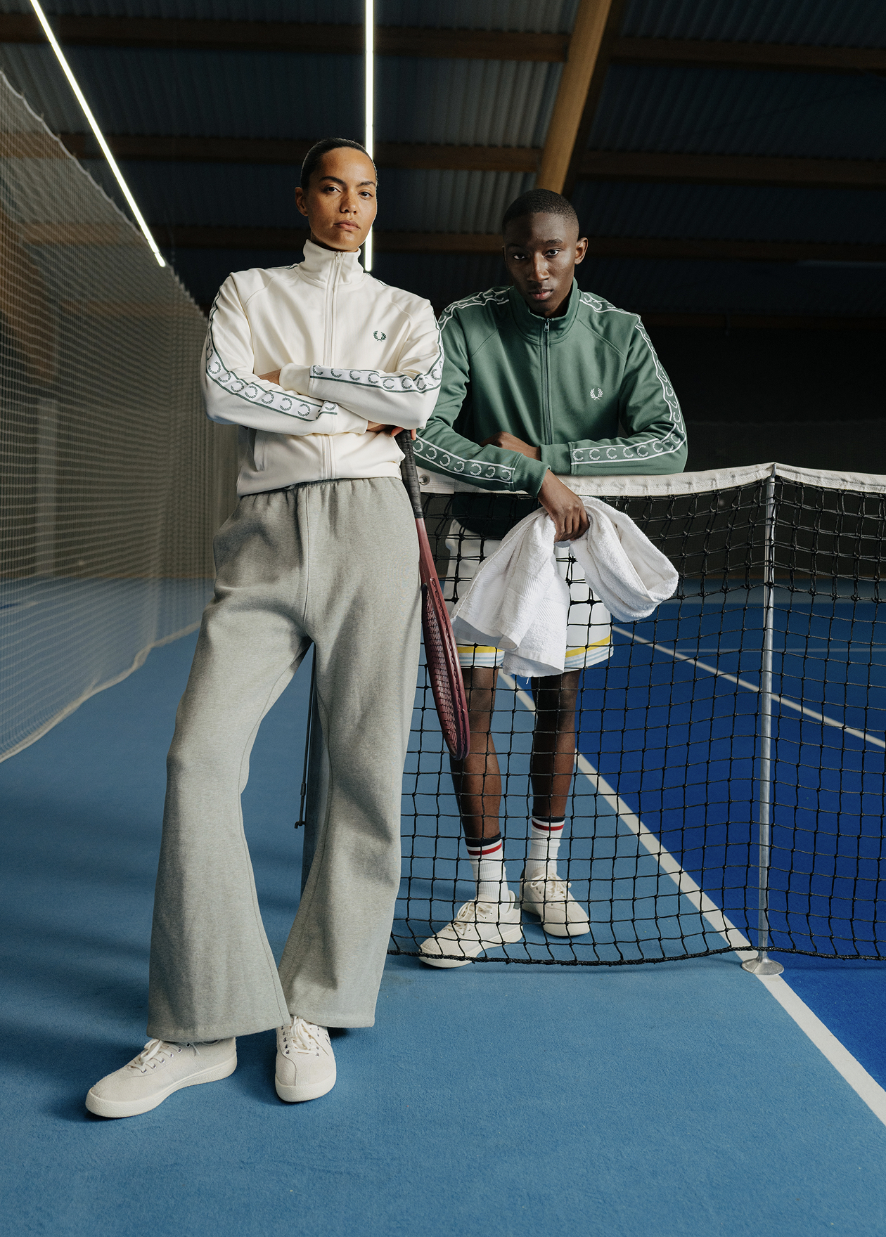 A male and female model wearing a Fred Perry Contrast Tape Track Jackets in Ecru and Sport Green
