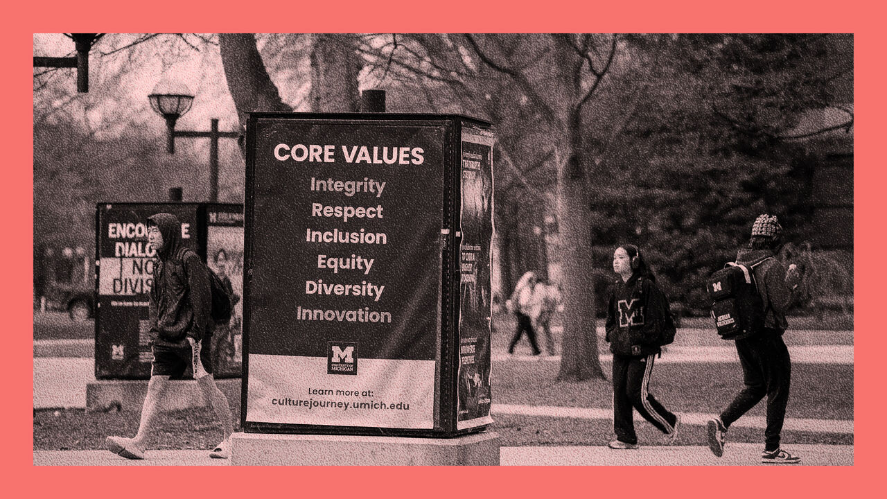 University of Michigan students walk on the UM campus next to signage displaying the University's Core Values in Ann Arbor, Michigan.
