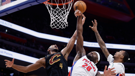 Basketball players jump for a ball.