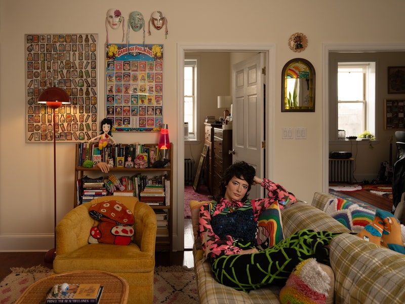 A woman rests on a couch near a yellow chair in her living room.