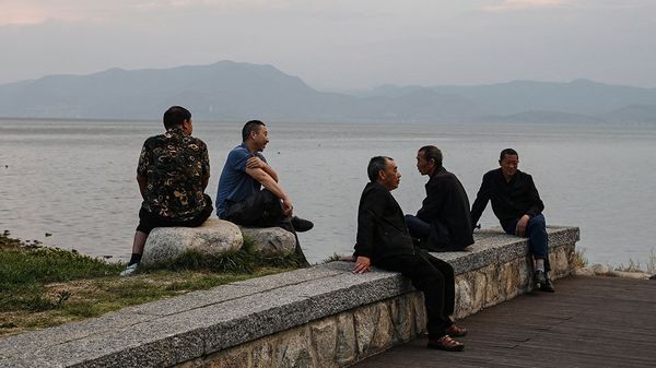 A group of men relax on the banks of Erhai Lake in Dali, Yunnan Province, China 