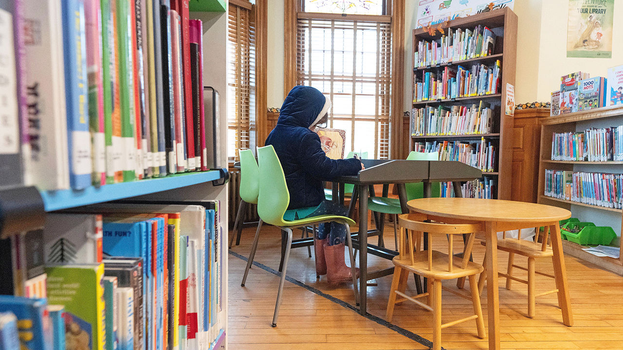 A young girl reads whilst sitting at a table situated on the Canada-USA international border line inside the Haskell Free Library and Opera House.