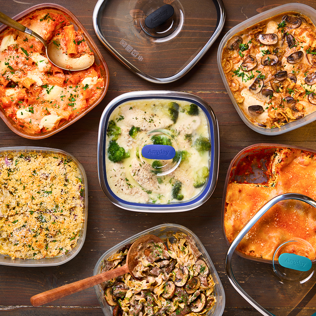 A spread of homemade casseroles cooked in the microwave, displayed in Anyday’s square dishes. The table features comforting dishes like lasagna, chicken with broccoli, beef stroganoff, and baked pasta, all topped with fresh herbs or crispy toppings. The Anyday lids are shown on several dishes, highlighting their versatility for microwave cooking.