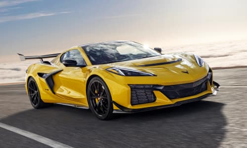 Three-quarter front view of a 2025 ZR1 Coupe in Competition Yellow Tintcoat Metallic cruising along a winding mountain road.