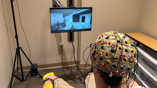 person with electrode cap looks at screen showing modern room