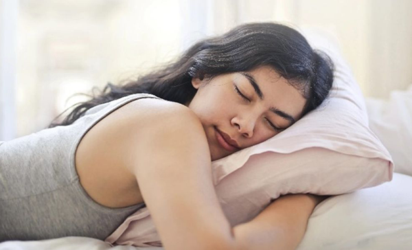 A young woman sleeps in a bed.