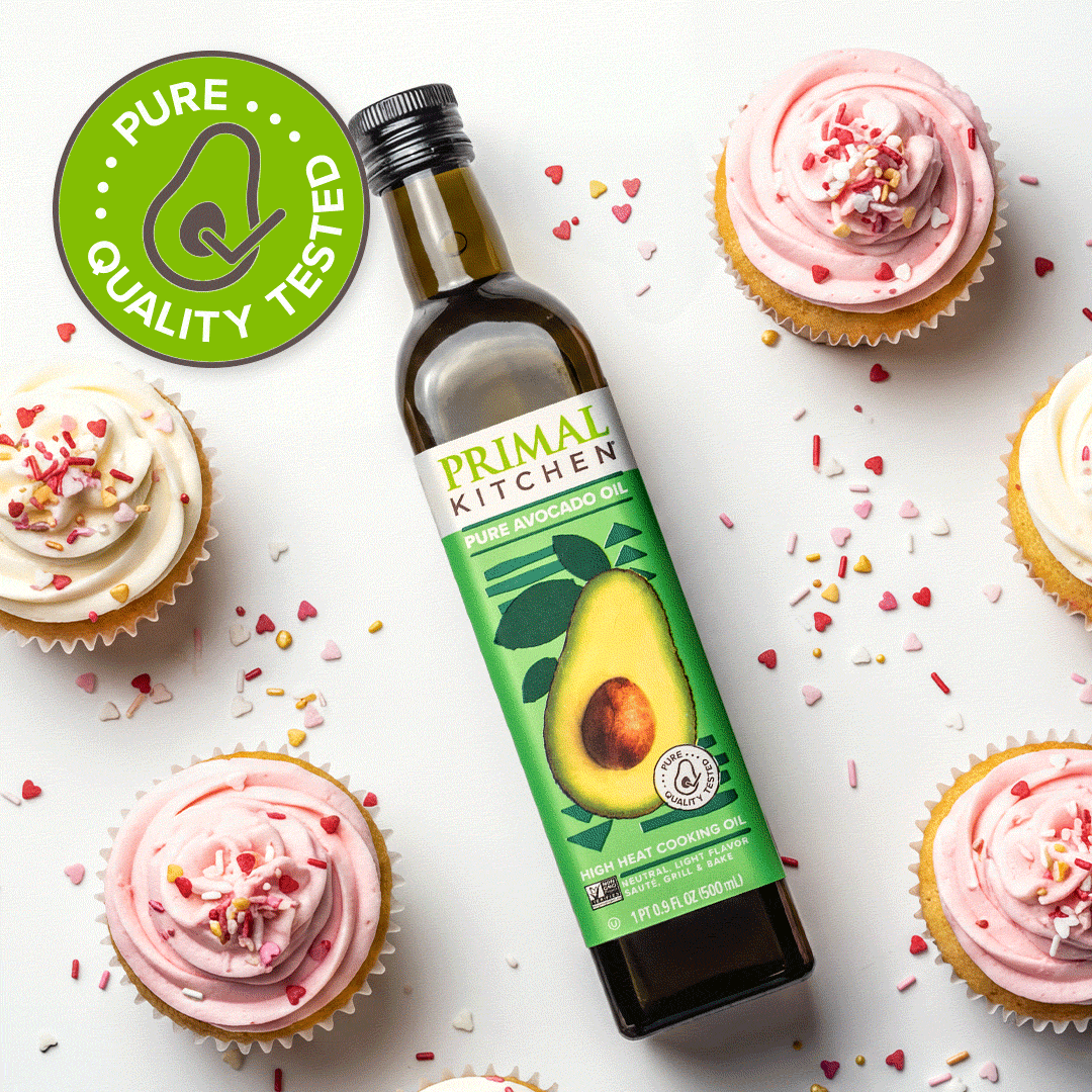 Primal Kitchen pure avocado oil on a backdrop wwith valentines theme cupcakes with pink icing and sprinkles
