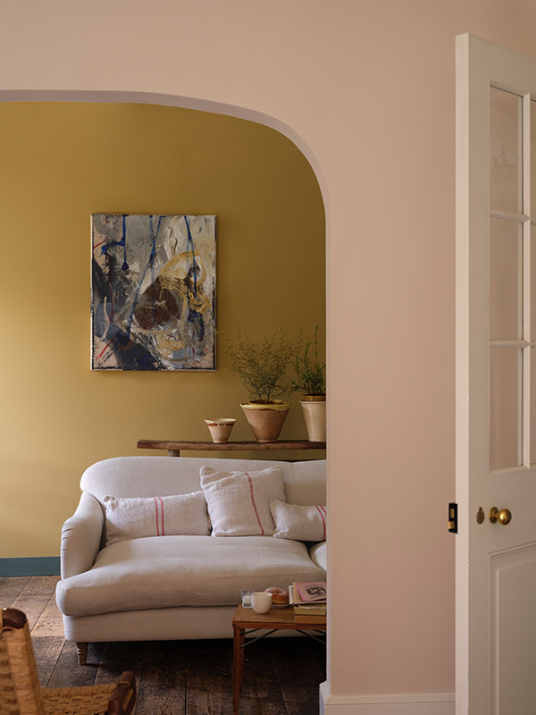 A living room with light yellow walls and a pale pink arched doorway.