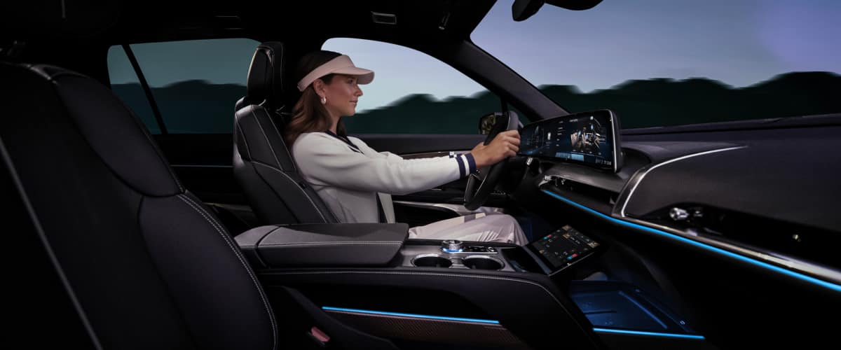 Passenger side view of a woman driving the 2026 Cadillac VISTIQ Luxury Electric SUV
