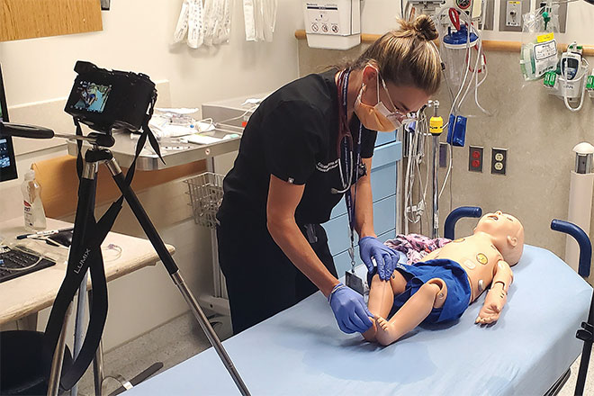 Elizabeth Sanseau maneuvers a child while being recorded by a camera for a training video. 