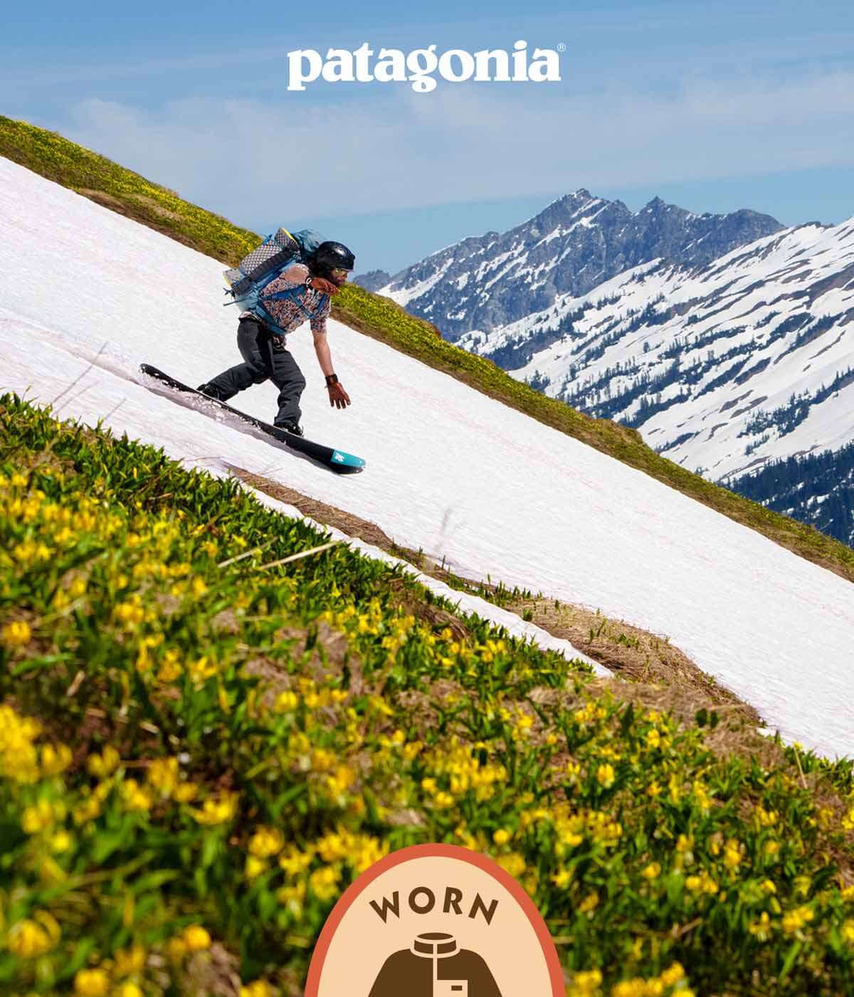 Patagonia Worn Wear. A person snowboarding on a patch of snow running through flowers.