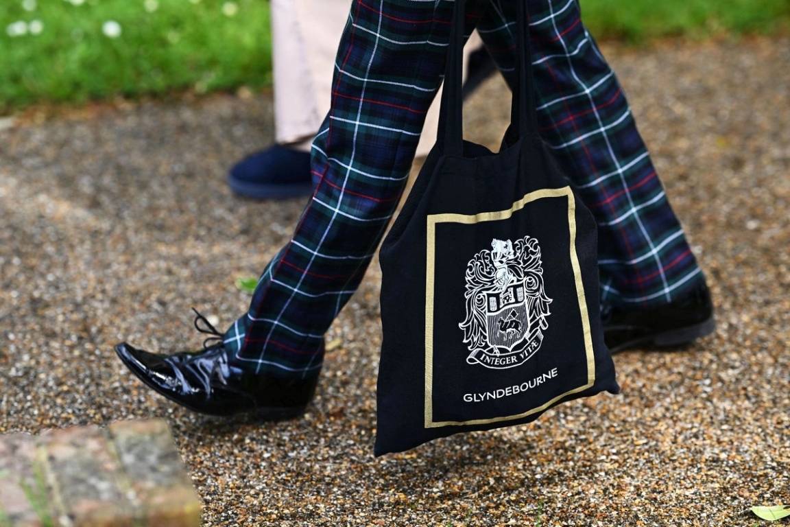 An opera fan carries a Glyndebourne tote bag. 