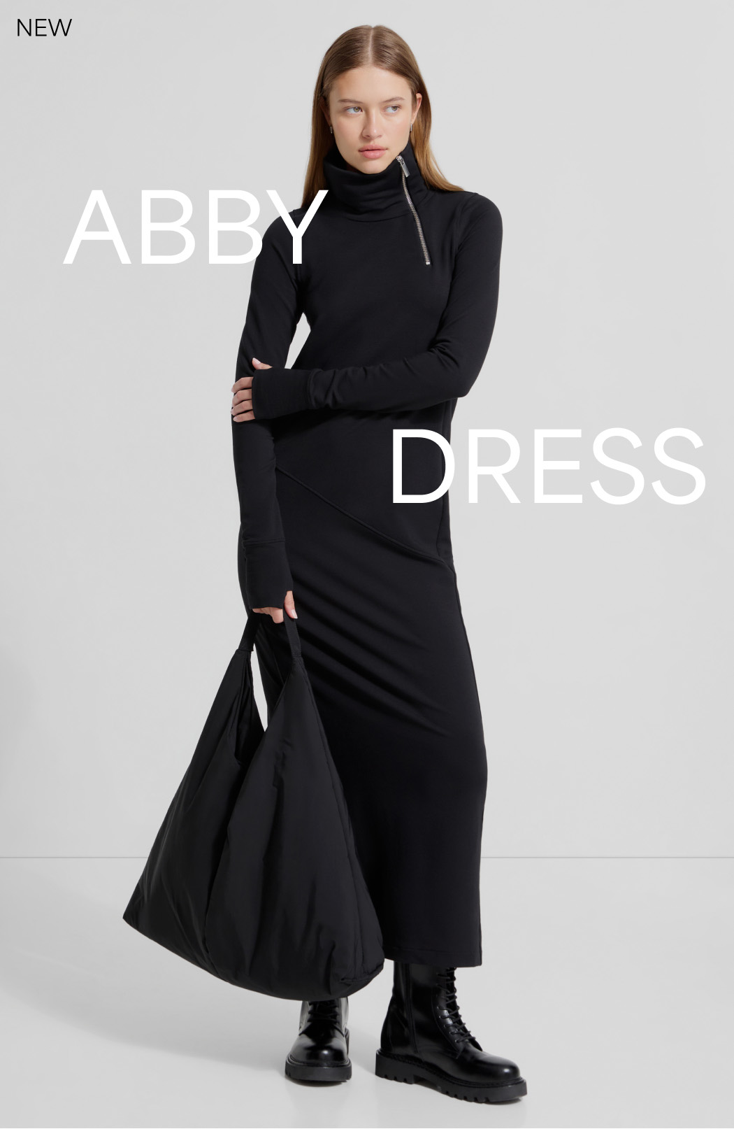 Bianca in The Abby Sweatshirt Dress with side zipper detail holds a slouchy black tote.