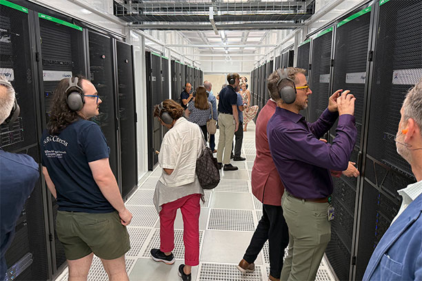 People wearing headphones walk through the halls of "Betty," a supercomputer.