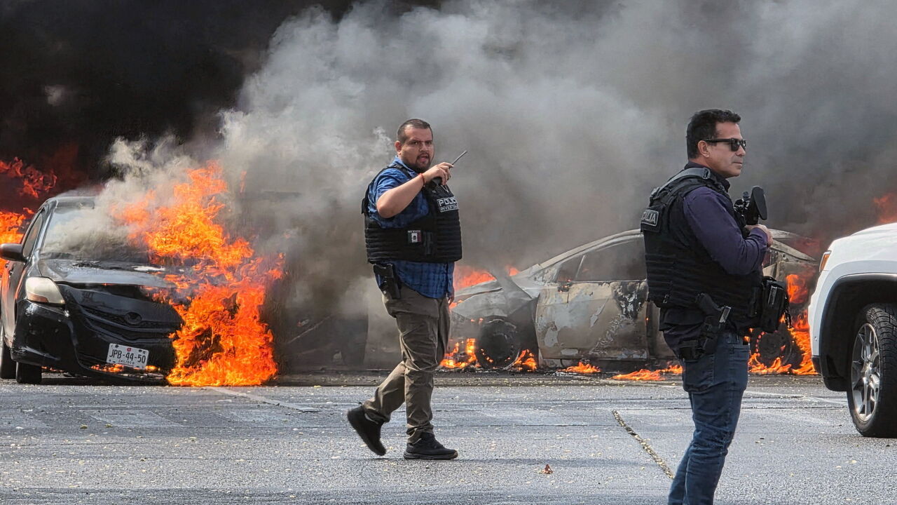 Police officers secure the area where vehicles were set on fire by organized crime members