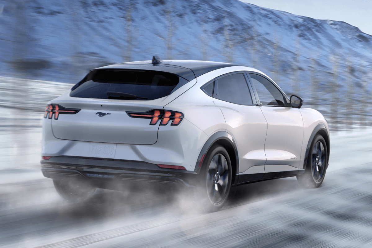 A Ford electric vehicle being driven down a snowy mountain road.