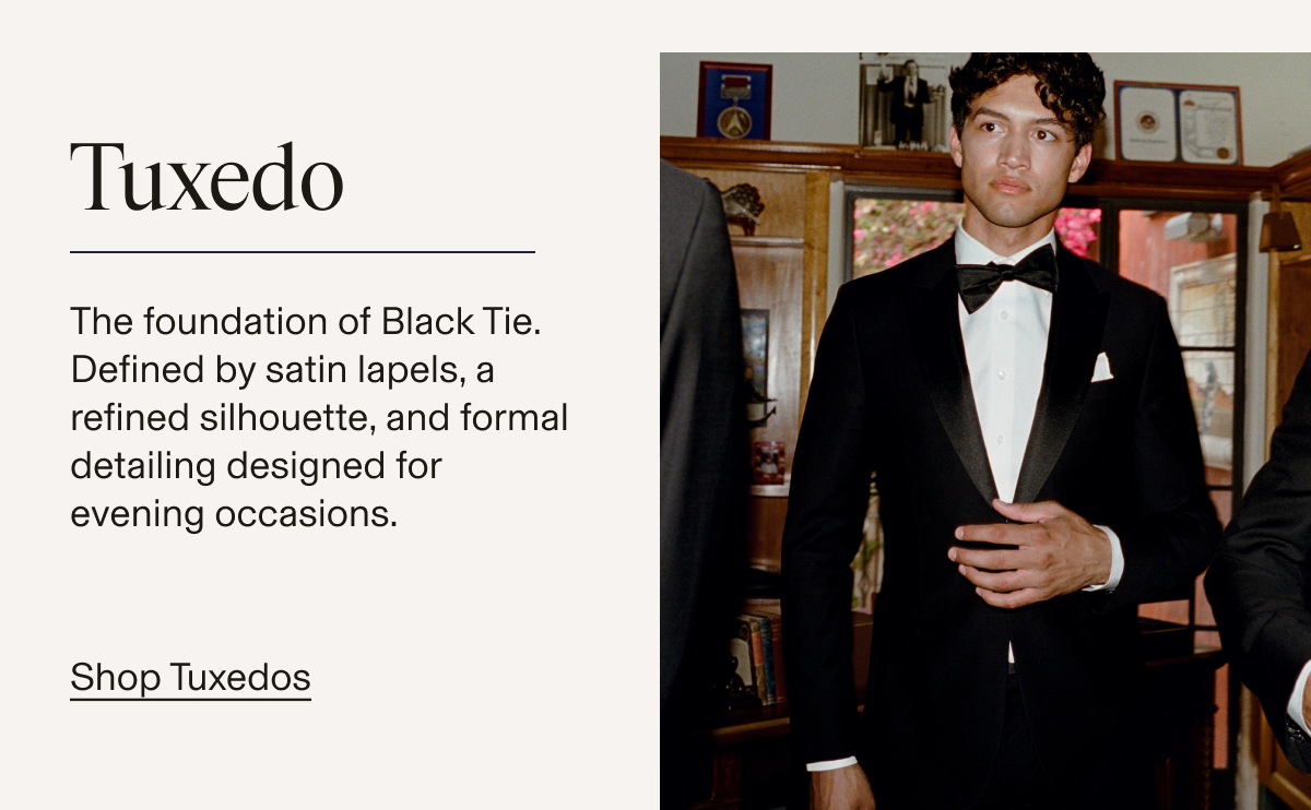 Male model wearing a black tuxedo with peak lapels, a white formal shirt, black bow tie, and white pocket square, standing in a warmly decorated room. Text reads: "Tuxedo. The foundation of Black Tie. Defined by satin lapels, a refined silhouette, and formal detailing designed for evening occasions. Shop Tuxedos"