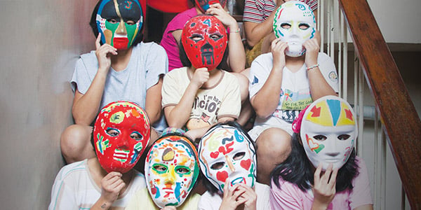 Girls hold the colorful masks they created over their faces. 