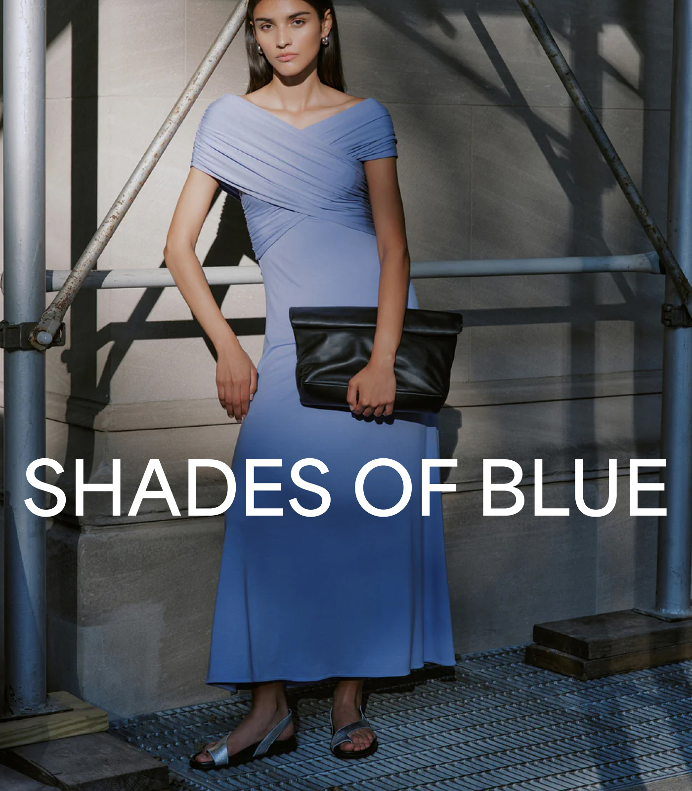 Sarah in The Alyssa Infinity Dress holds a black clutch with the text “SHADES OF BLUE.”