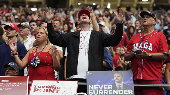A large cowd of people raise their hands in praise.