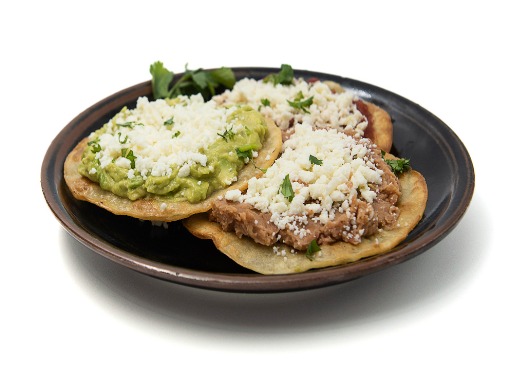 Tostadas with beans and guacamole on a plate.