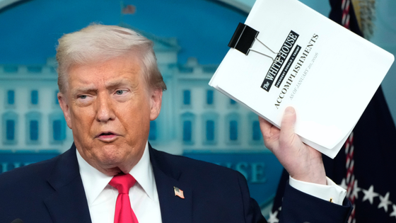 Trump holds up a sheaf of papers with the header 