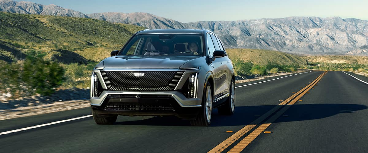 The 2026 Cadillac VISTIQ All-electric SUV driving down a road in the mountains