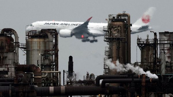 A Japan Airlines (JAL) airplane flies past an oil refinery as it approaches to land at Tokyo's Haneda airport, as seen from a park in the Keihin Industrial Zone in Kawasaki, south of Tokyo, Japan.
