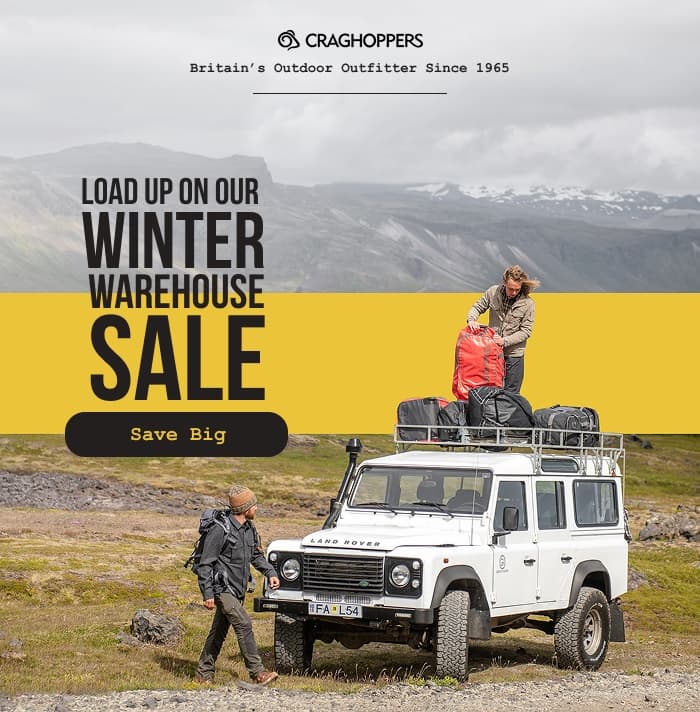 Man loading duffel bags onto the top of a classic Land Rover Defender: Load up on our winter warehouse sale: Save big.