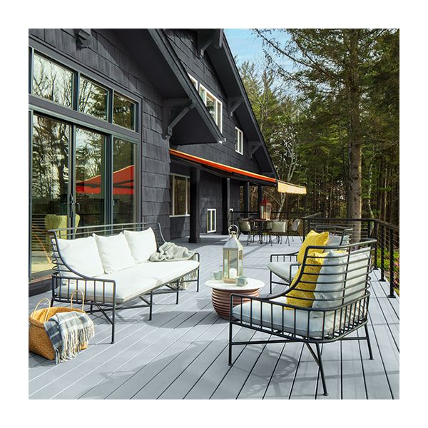 The back of a dark gray exterior sided home with a spacious light gray stained deck and white outdoor furniture.