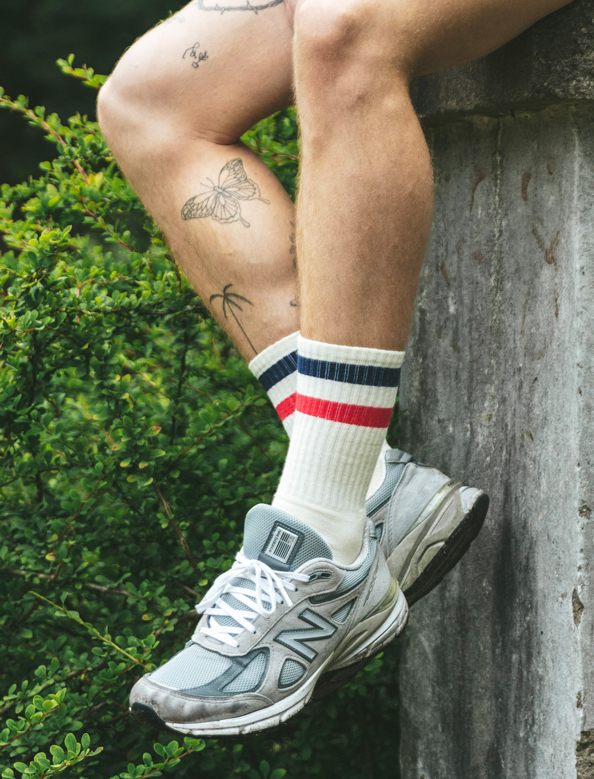 man sitting on ledge wearing blue and red striped tech varsity crew socks