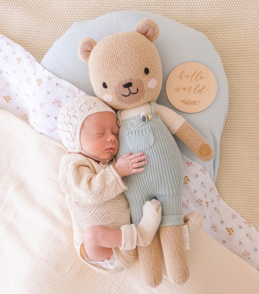 Baby cuddling Charlie the honey bear