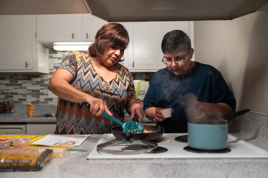 Junior and his mother, Elodia, standing in front of the stove cooking together.