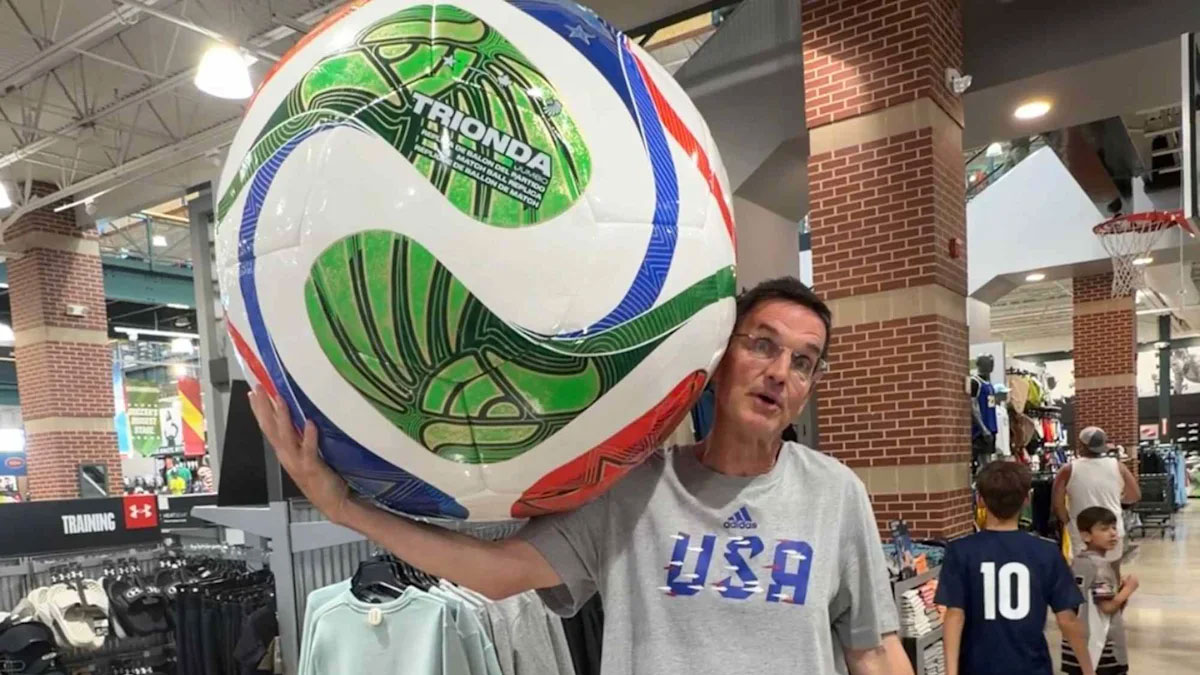 A man holds a giant soccer ball.