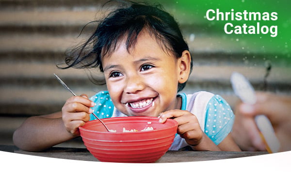A girl with rice grains on her mouth smiles over a bowl of Vitafood.