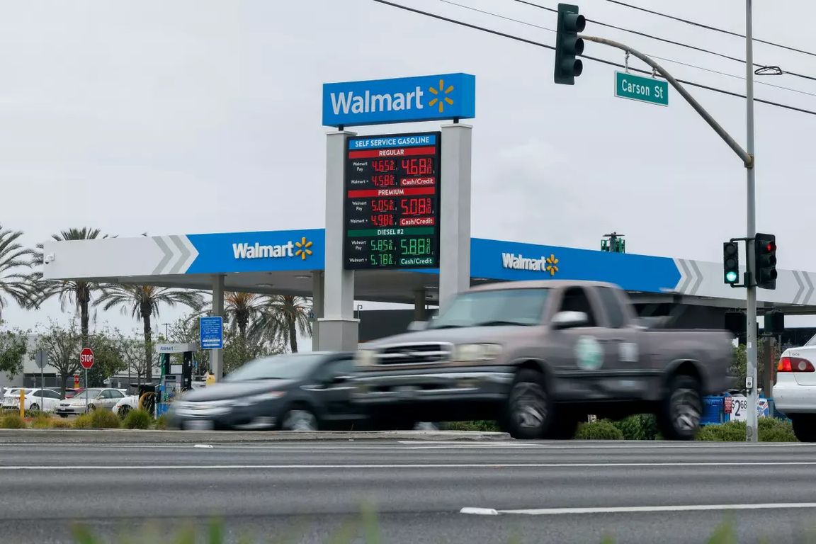 Vehicles drive past a Walmart gas station in Southern California as a roadside sign displays prices for regular, premium and diesel fuel.