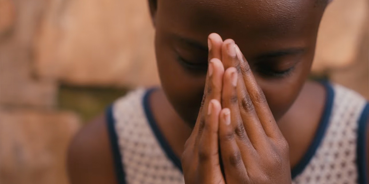 A child humbly prays with eyes closed