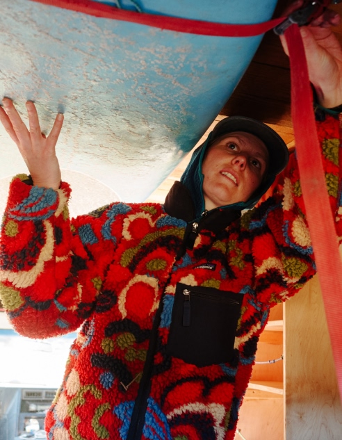 A person loads a surfboard in a van.